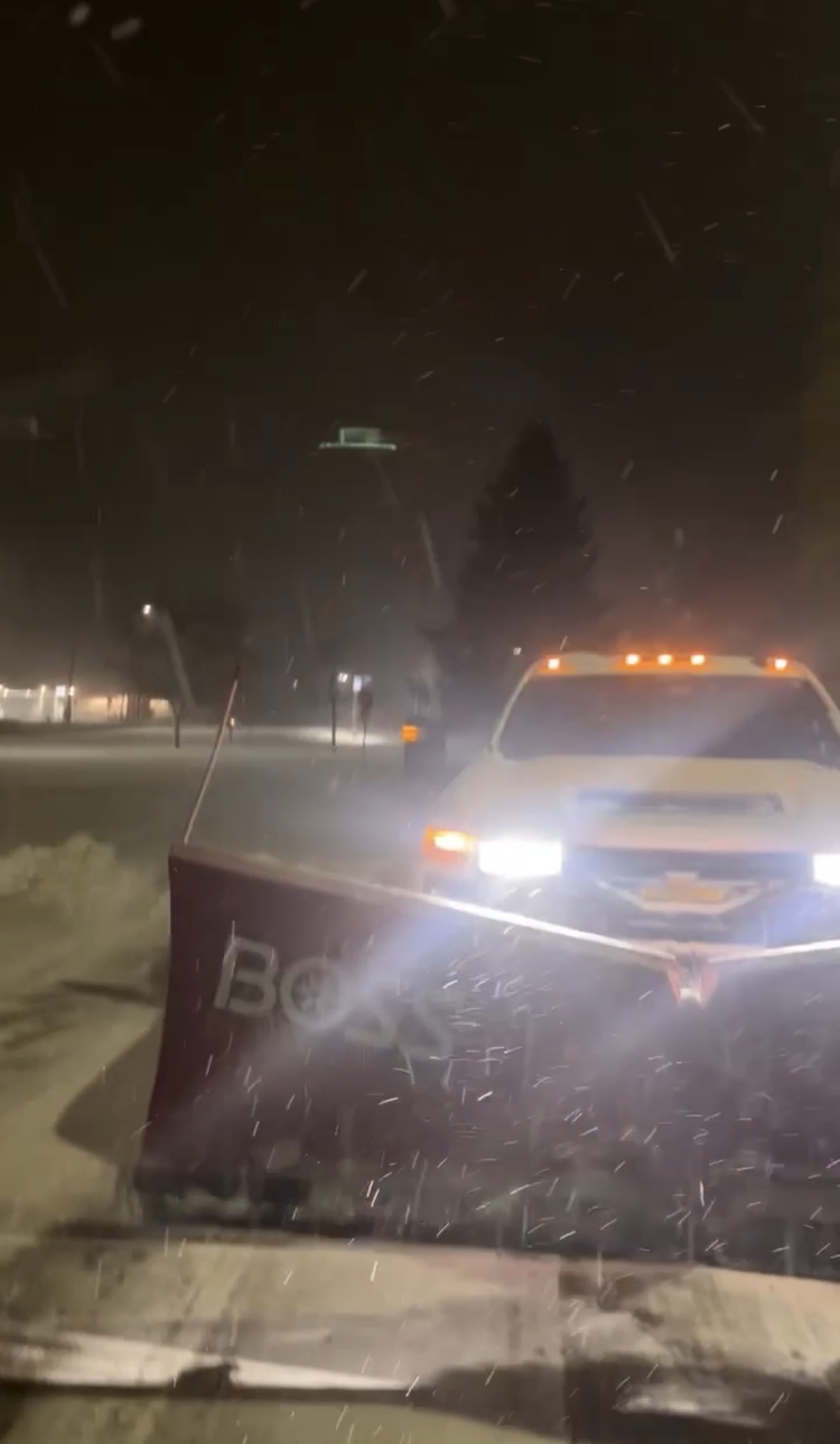 Swift snow plow truck with a BOSS plow clearing a commercial lot at night
